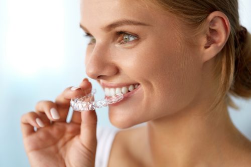 smiling woman with invisalign clear braces in her hand